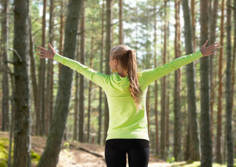 Dievča v zelenej mikine počas prechádzky v lese